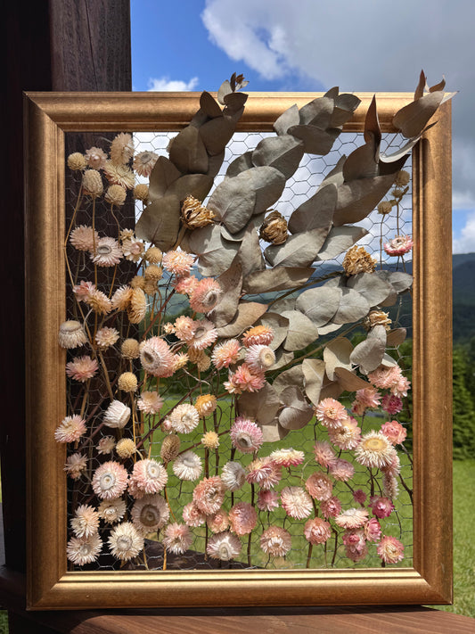 Framed artwork with dried flowers and leaves against a natural background